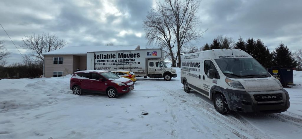 Reliable Movers trucks parked at a snowy residential property, showcasing commercial and residential moving services during winter conditions.