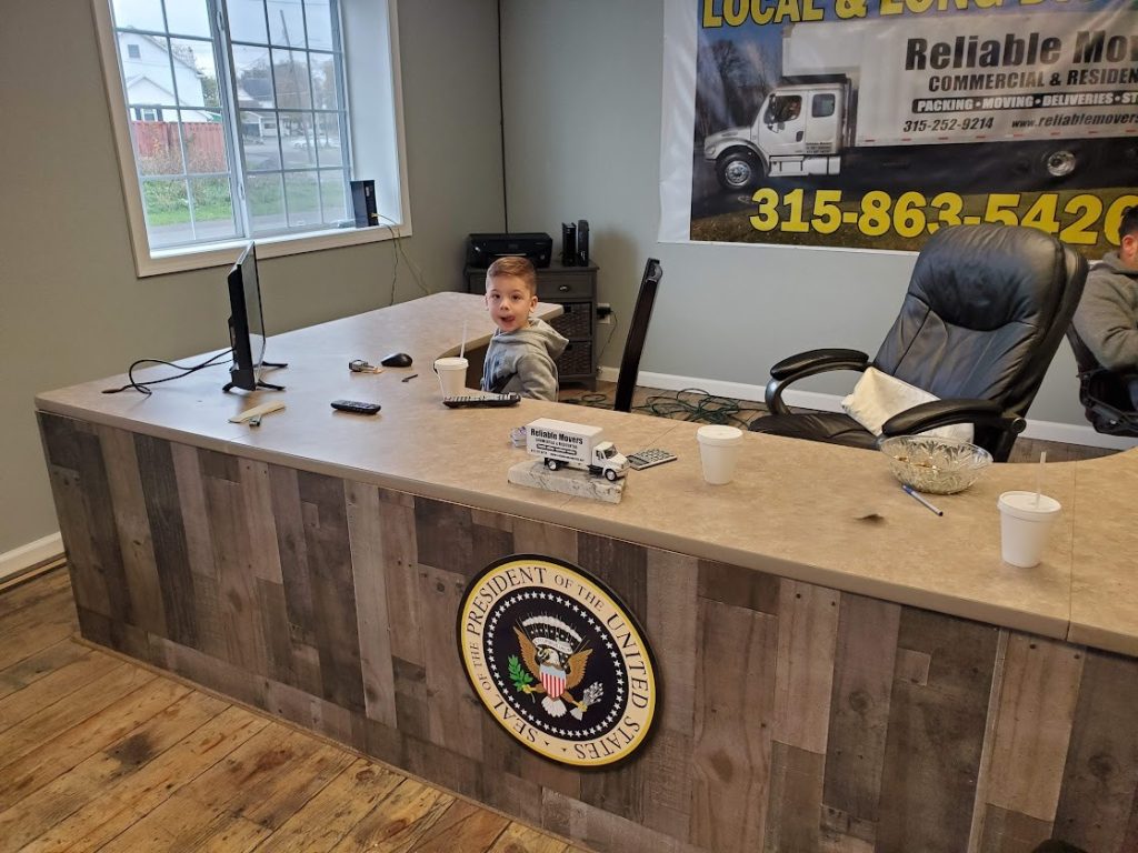 Grandson Vincent sitting at desk helping run moving office during COVID
