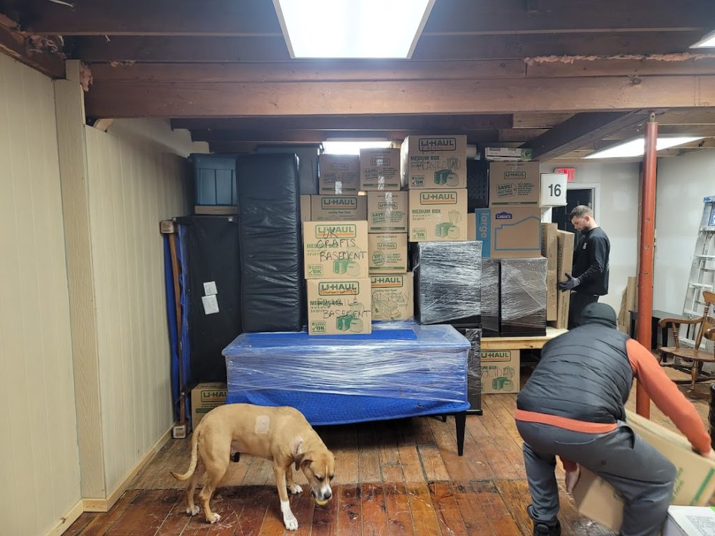 Company dog Gino supervising movers unloading boxes in storage warehouse