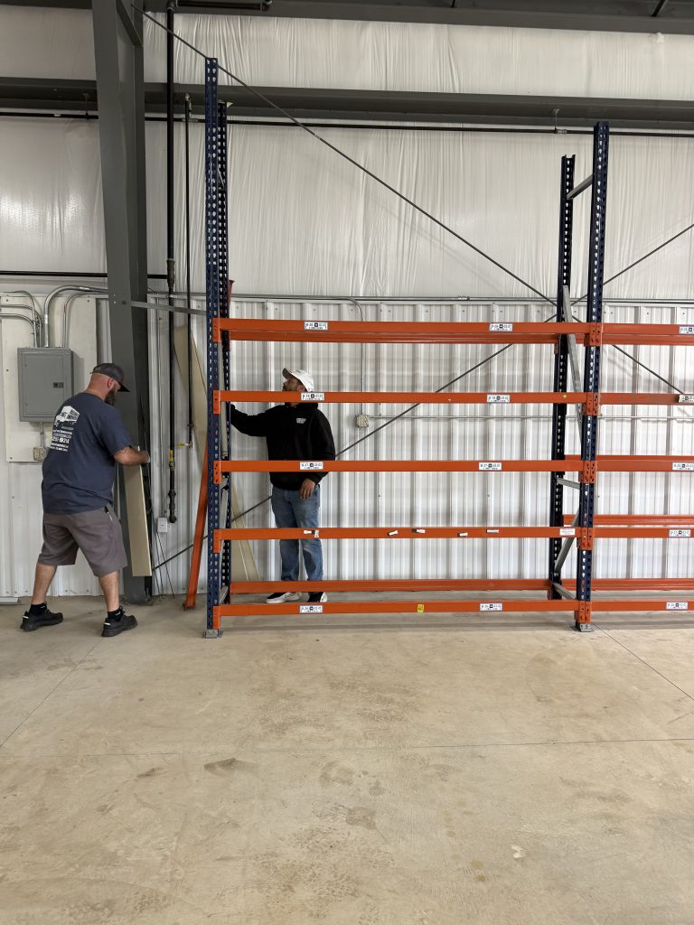 Reliable Movers assembling heavy-duty warehouse shelving during a commercial move in Buffalo, NY.