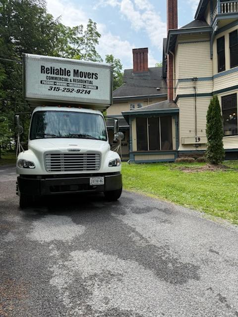 Reliable Movers 30-foot moving truck parked in front of a large historic Victorian home in Clinton, New York.
