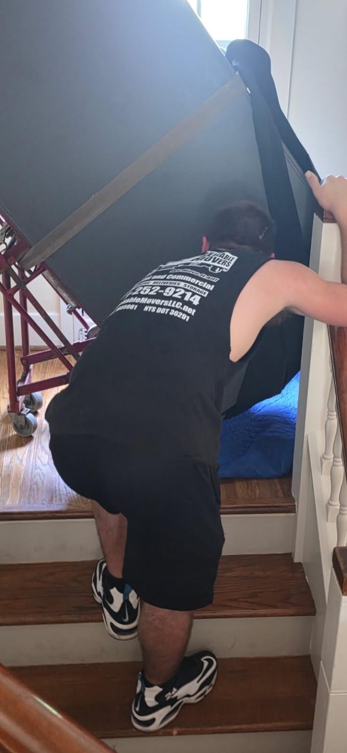 Reliable Movers moving a heavy gun safe through a Rochester NY home
