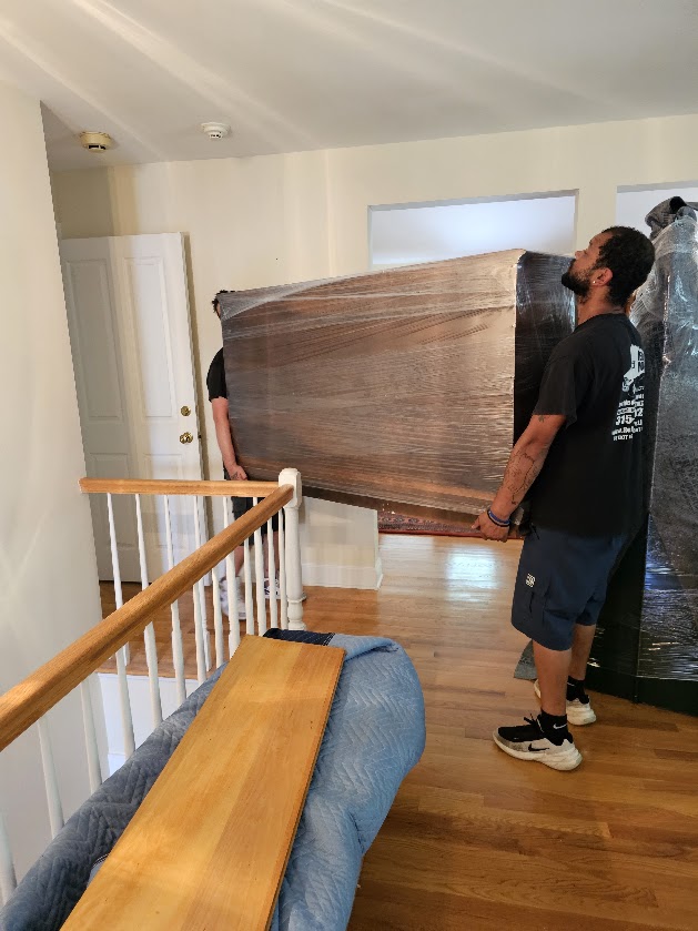 Reliable Movers crew carrying a protected dresser during a local move in Manlius New York