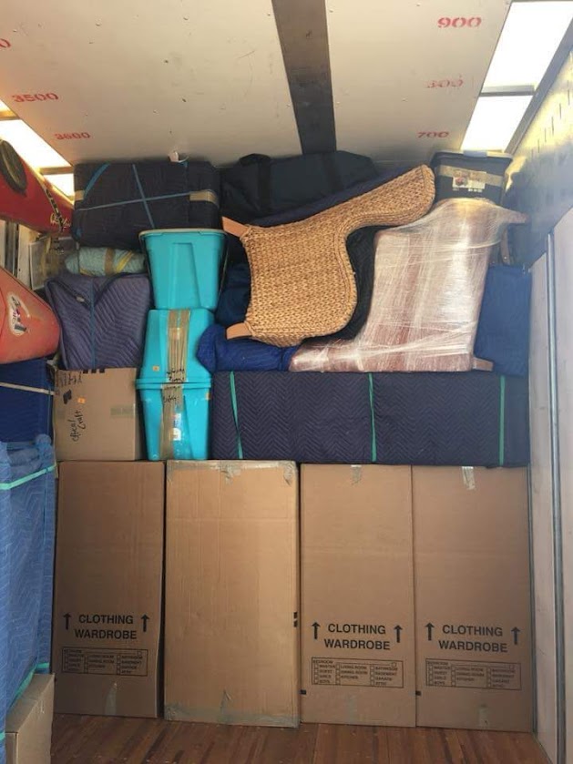 Reliable Movers professionally loading furniture and boxes into a customer rental moving truck